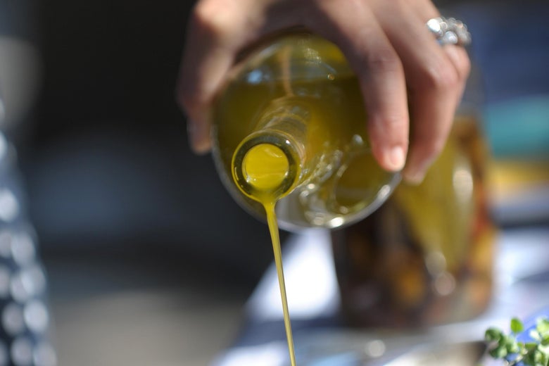 Olive oil being poured out of a bottle.